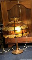 Front view of lamp illuminated on dark surface showing stained glass shade and brass base