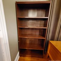 Front view of wooden bookcase showing four shelves and medium brown finish.
