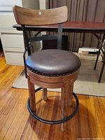 Full view of the counter height swivel stool showing the padded seat, wooden backrest, and metal frame with footrest.