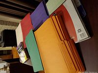 Photo showing multiple colored legal sized file folders and the Quickbooks Online for Dummies book.