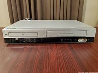 Front view of LG VCR/DVD player combo showing DVD tray and VCR slot with control buttons and input jacks.