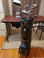Full view of men's golf clubs set in a brown leather golf bag from the front.