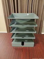 Front view of the steel document tray showing all five stacked tiers with the circular and rectangular cut-outs.