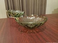 Side view of vintage green-tinted glass chip and dip bowl set on table with curtains in background.