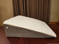 Side view of gray wedge pillow showing inclined profile and quilted fabric texture