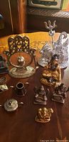 Several Indian-themed brass and silver-colored figurines grouped on a wooden surface, showing various sizes and intricate detailing