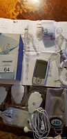 Photo of the device along with electrode pads, charger, and instruction manual spread on a table.