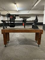 Front view of Shop Smith wood lathe on rolling wooden bench in a garage setting, showing full machine and bench.