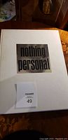 Front cover of the large white hardcover photography book titled 'nothing personal' with metallic inset