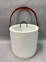 Front view of the vintage white faux leather ice bucket with lucite handle and lid pull.
