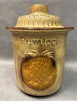 Close-up front view of ceramic jar crock showing 'Rumtopf' embossing and fruit motif, lid on.