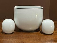 Front view of Rosenthal Studio-Line Suomi white open vegetable bowl centered with salt and pepper shakers on either side, showing smooth rounded shapes and anthracite detail near rims.