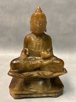 Front view of the jade Buddha carving showing facial features, seated posture, lotus base, and rectangular plinth.