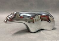 Side view of the polished aluminum polar bear sculpture showing smooth, reflective surface and stylized design.