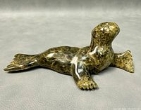 Side angle showing the carved details of the seal's flippers and natural soapstone veining.
