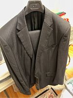 Full view of Armani Collezioni pinstripe jacket and matching trousers on hanger