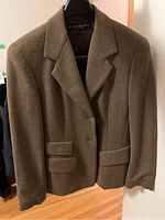 Brown women's blazer hanging on black plastic hanger
