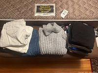 Photo of all items folded including pants, jeans, sweaters, and shirts arranged on a brown surface.