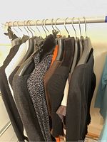 Multiple women's sweaters on hangers in assorted colors and styles including animal print, black, brown and white knits.