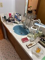 Photo showing the bathroom counter with all items including curling iron, cosmetic containers, hair clips, q-tips, soap dish, and soap pump.