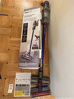 Full kit laid out: boxed dock, manuals, main vacuum attached to wand, two brush heads side by side