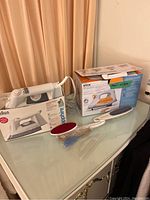 Overview of two boxed irons and fabric brushes on tabletop