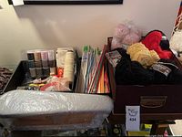 Photo showing assorted yarns, knitting needles, pressing arm, sewing threads and notions in storage boxes.