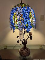 Full view of lamp lit, showing stained glass shade and sculpted tree base
