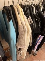 Rack of assorted women's tops including light blue cardigan, lace tops, black sleeveless tops, and patterned top.