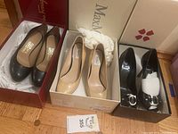 Three pairs of designer shoes including Ferragamo black closed pumps in red box, MaxMara nude pumps in white box, and Christian Dior black open-toe pumps with silver buckle in branded box.