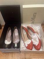 Two pairs of women's designer shoes in their boxes: coral MaxMara heels size 36 and black Ferragamo patent leather heels size 5.