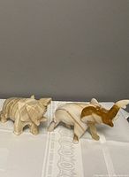 Two large onyx elephant figurines displayed side by side on patterned cloth, showing front and side views