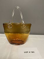 Full front view of the amber handblown art glass purse showing its shape, color, and clear handles.