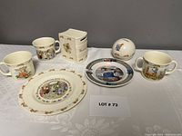 View of all Bunnykins collection items including plates, mugs, and coin banks displayed on lace cloth.