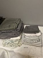 Folded bedding and pillowcases display showing variety of colors and patterns including solid, stripes, floral