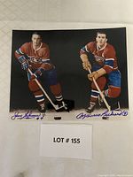 Photo showing autographed 8x10 photos of Jean Beliveau #4 and Maurice Richard #9 in Canadiens uniforms, displayed on white surface with lot number card.