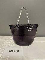 Full front view of the purple art glass purse with clear glass handles showing the overall shape and size.