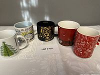 Front view of five collectible Starbucks mugs with various designs.