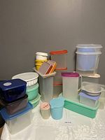 Overview of 22 plastic food storage containers including Tupperware, Rubbermaid, and Anchor Hocking, showing multiple colors, sizes, and shapes stacked together.