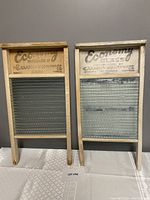 Photo showing two vintage wooden wash boards with glass scrubbing inserts and printed wood top with company details.