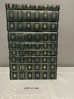 Stack of nine vintage hardcover green books with gold embossed titles on the spine from The Programmed Classics series.
