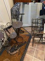 Photo showing vintage octagonal etched mirror with three wrought iron candle stands and iron magazine rack on tiled floor.