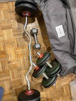 Top view showing assembled curl barbell with weight plates, dumbbell, and carrying bag.