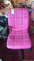 Front view of pink computer chair showing cushioned grid pattern and damage on the seat and backrest.