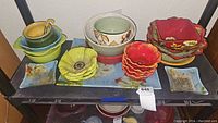 Overview shot of all dishware on a table showing varied shapes, sizes, and colors of poppy-themed ceramics.