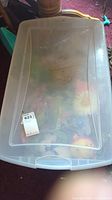 Clear plastic storage bin containing assorted Easter decorations and crafts beneath a closed lid.