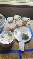 Full set including cups, saucers, plates, sugar bowl, creamer, arranged on a wooden surface.