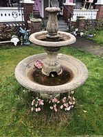 Full view of assembled 4 piece cement water fountain in garden setting with visible moss and water standing in basins.