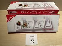 Photo of two boxes stacked, showing the tray with 6 spoons packaged inside. The boxes branded 'Brilliant' and labeled 'A Taste of...' and 'Tray with 6 Spoons'.