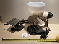 Antique kitchen scale and vintage electric mixer side by side on a shelf with measuring tape in front